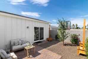 Il s’agit d’une propriété résidentielle dotée d’un patio, d’un espace extérieur aménagé pour s’asseoir, d’une porte-fenêtre coulissante et d’un petit jardin.
