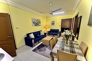 Una sala de estar con dos sofás, una mesa de centro y una mesa de comedor con sillas.