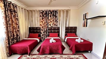 A hotel room with three beds, a ceiling fan, and a patterned rug.