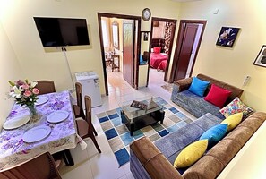 Un salon comprenant un canapé, une table basse et un coin repas avec une table dressée pour quatre personnes.