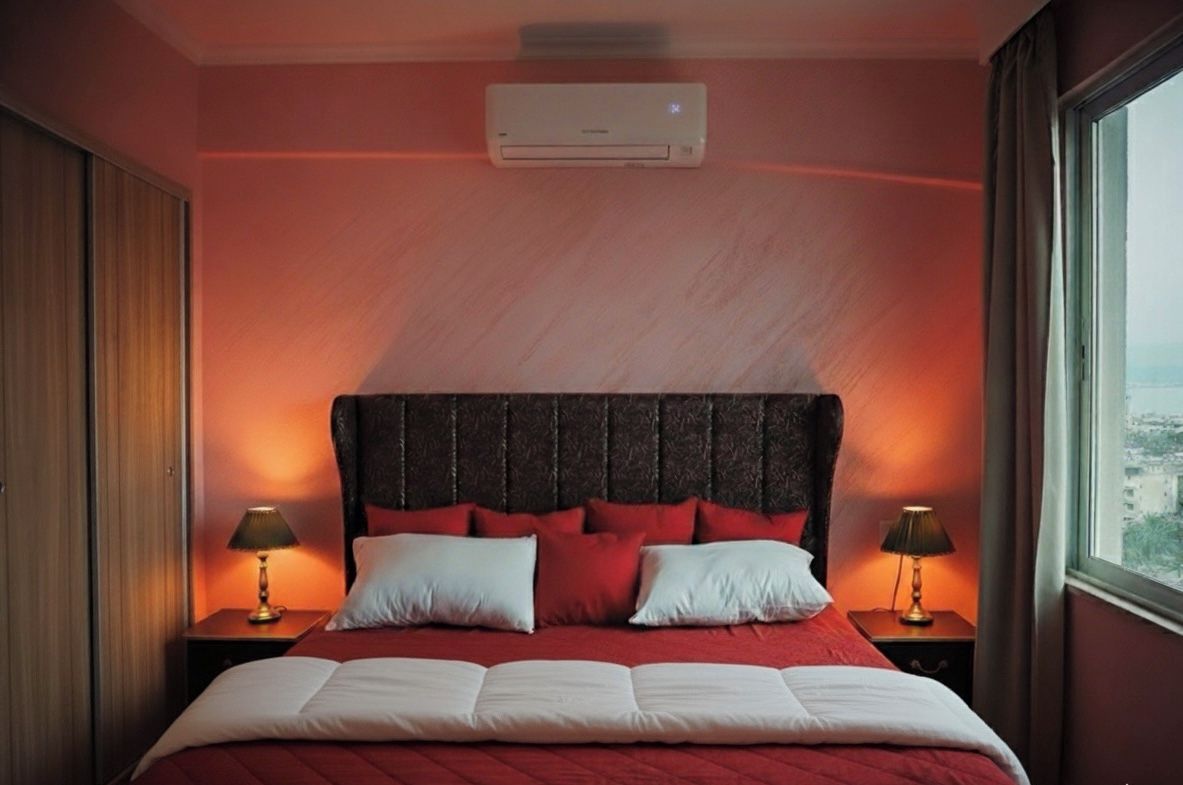 Habitació d'hotel amb un llit gran, dues taules de nit, un aparell d'aire acondicionat i una finestra amb vistes.