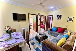 Un salon comprenant un canapé, une table basse et un coin repas avec une table dressée pour quatre personnes.