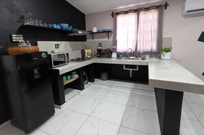Eine moderne Küche mit einem schwarzen Kühlschrank, einer Mikrowelle, einem Toaster und einem Spülbecken.