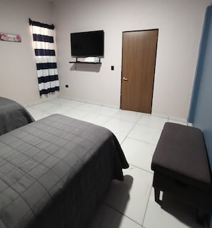 A room with two beds, a television mounted on the wall, a wooden door, and a curtain. - Casa Tabor, Lereto Center (Loreto)