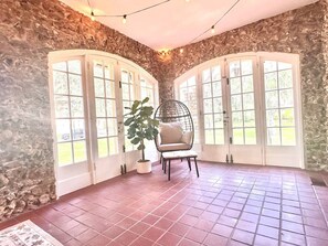 A room with stone walls, a tiled floor, a hanging chair, and a potted plant. - The Cobblestone Estate - Historic Downtown Ocala! (Ocala)