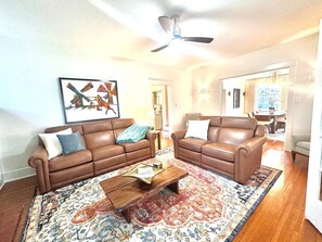 A living room with two brown leather sofas, a coffee table, and a patterned rug. - The Cobblestone Estate - Historic Downtown Ocala! (Ocala)