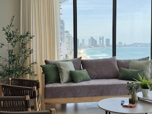 Een moderne woonkamer met uitzicht op de oceaan en een stadshemelbeeld.