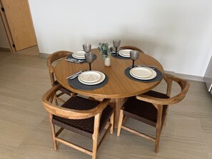 A round wooden dining table with four chairs, each with a woven seat cushion. - Luxury Oceanfront Apartment: Elegance and Relaxation byGPS (Mazatlán)