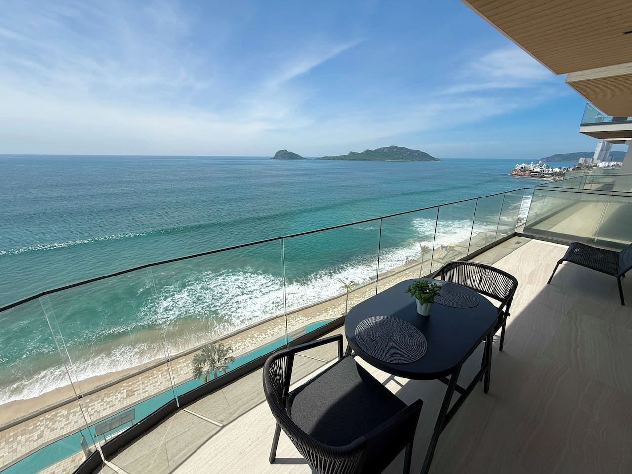 Varanda com mesa e cadeiras de frente para uma praia e oceano.