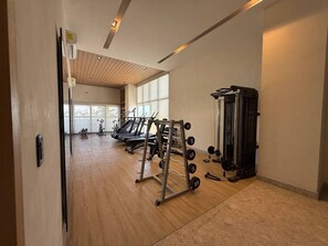 A gym with exercise equipment, a treadmill, and a weight rack. - Luxury Oceanfront Apartment: Elegance and Relaxation byGPS (Mazatlán)