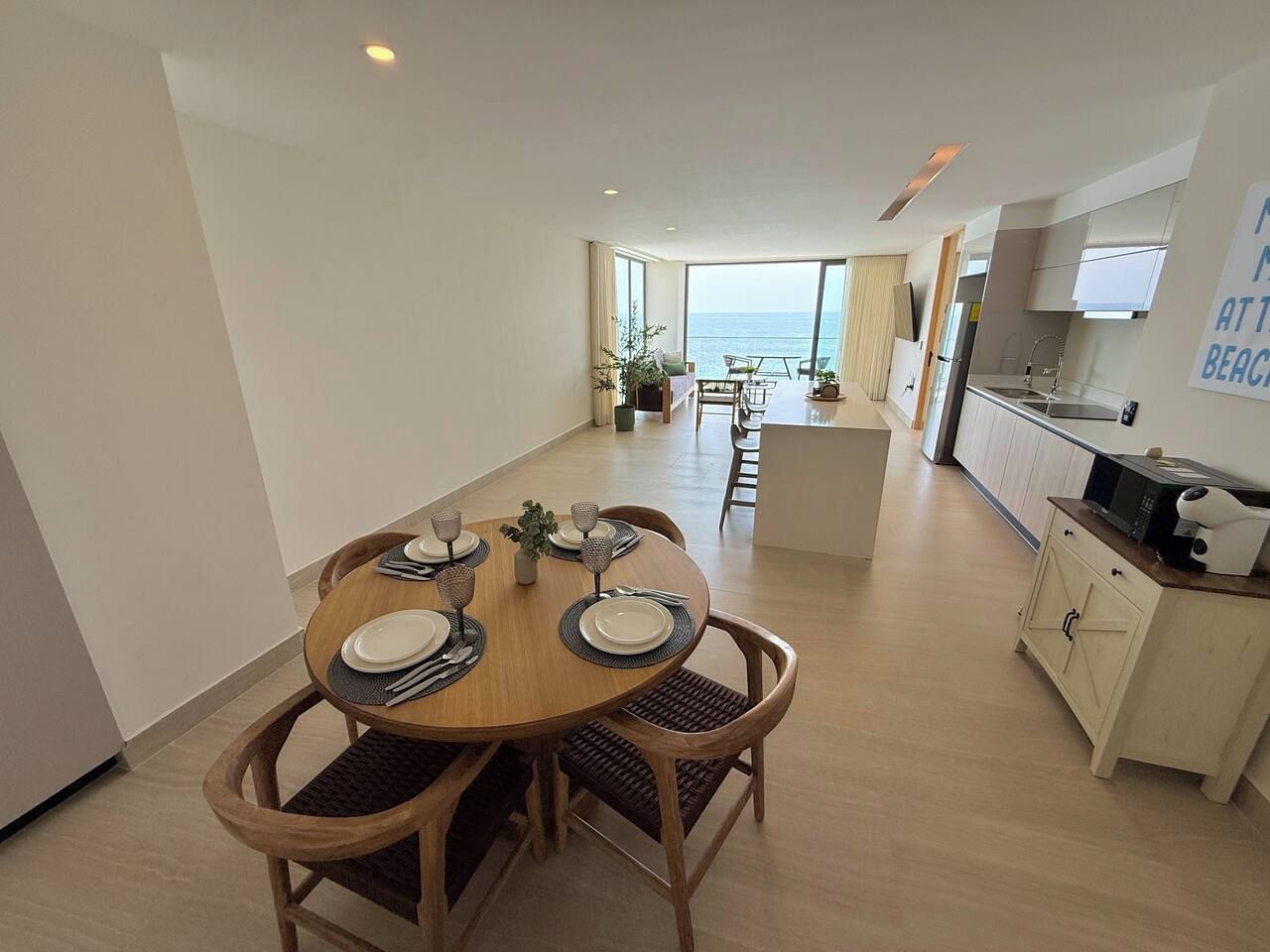 Un appartement moderne doté d’un coin repas, d’une cuisine et offrant une vue sur la mer.