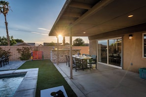 Ein überdachter Patio-Bereich mit Pool, Sitzgelegenheiten im Freien und Blick auf den Sonnenuntergang.