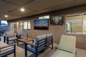 Ein Außenbereich mit Sitzgelegenheit, einer Wandmalerei, einem Dartspiel und Blick auf ein Gebäude.