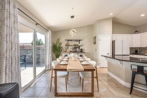 Una cucina moderna con mobili bianchi, un piano di lavoro nero e un'area pranzo con tavolo e sedie in legno.