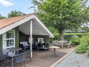 A covered outdoor seating area with tables and chairs, a barbecue grill, and a large tree providing shade. - "Dior" - 800m from the sea by Interhome (Hejls)