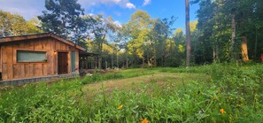 A wooden cabin with a porch, surrounded by a forested area. - Starry Pines Cabin: A handmade cozy cabin-near waterfall, dogs welcome (Blountsville)