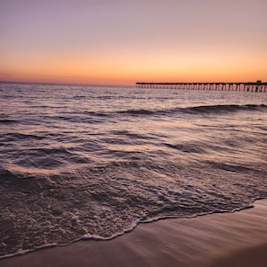 A beach with waves and a pier extending into the water. - Seahorse House - Coastal Charm, Community Pool & Beach Days (Panama City Beach)
