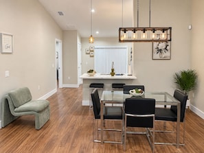 A modern dining area with a glass table, black chairs, and a pendant light fixture. -  The Chosen Experience (Palm Coast)