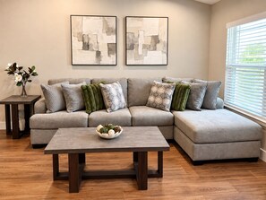 A modern living room with a sectional sofa, a coffee table, and abstract art on the wall. -  The Chosen Experience (Palm Coast)