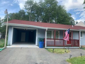 A residential building with a garage, a red porch, and an American flag. - Cozy 2-bedroom house in fabulous in Pocono Mountain (Tobyhanna)