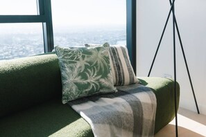 A green sofa with a patterned pillow and a striped throw blanket. - Elegant 2BR Broadbeach Island Getaway (Broadbeach)