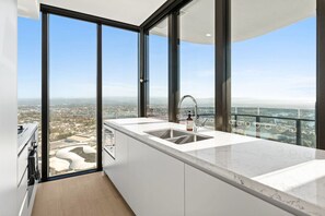 A modern kitchen with a large window, a sink, and a view of a cityscape. - Elegant 2BR Broadbeach Island Getaway (Broadbeach)
