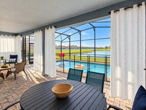 A covered outdoor area with a pool, chairs, and a table. - Epic 9BR Solara Villa w/ Cinema Movie Room (Kissimmee)