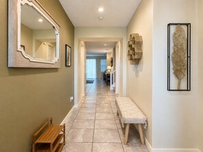 Un couloir avec un banc, un miroir et un élément décoratif mural.