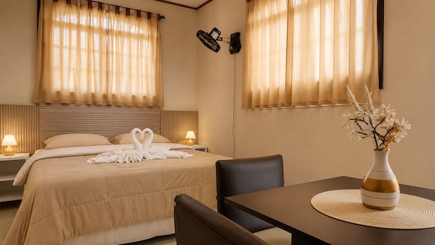 Une chambre d’hôtel comprenant un lit, deux tables de chevet, un bureau et une chaise.