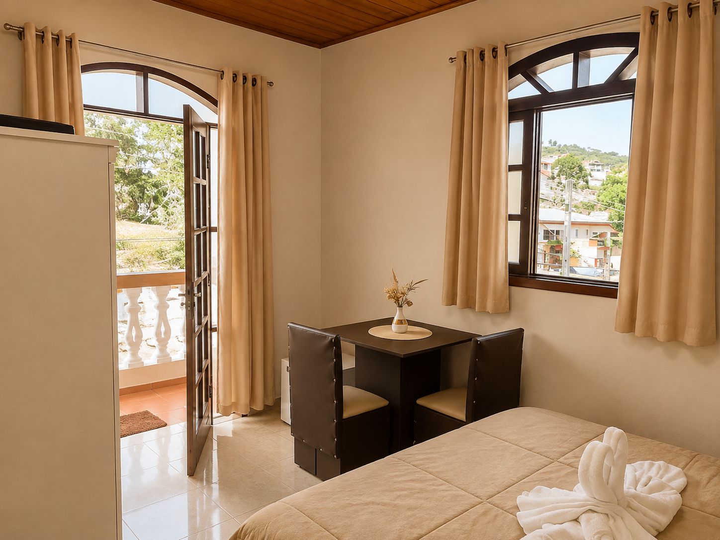 A hotel room with a bed, a desk with a chair, a window with curtains, and a view of the outside.