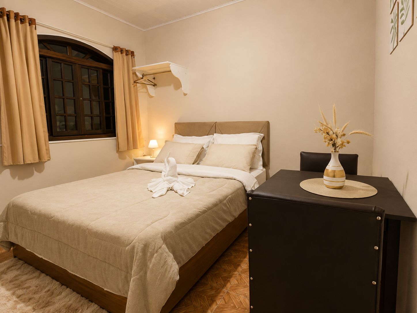 Una habitación de hotel con cama, mesita de noche, lámpara y un florero con flores.