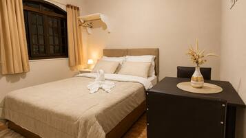 Una habitación de hotel con cama, mesita de noche, lámpara y un florero con flores.