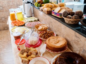 A buffet table with various food items including bread, pastries, and a cake.