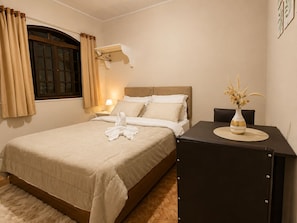 Una camera d'albergo con un letto, un comodino, una lampada e un vaso con fiori.