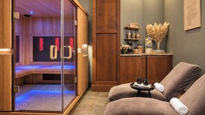 Ett spa-rum med bastu, en massagefåtölj och ett litet bord med en handduk.