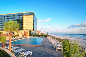 A modern hotel with a swimming pool, lounge chairs, and a beach view. - 3 Oceanview Studios connecting w/pool, tiki bar (Daytona Beach)