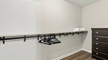 A closet with a black hanging rod and a dark wooden dresser.