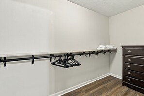 A closet with a black hanging rod and a dark wooden dresser. - Cozy Mid-City 1BR Home Near Casinos (Lake Charles)