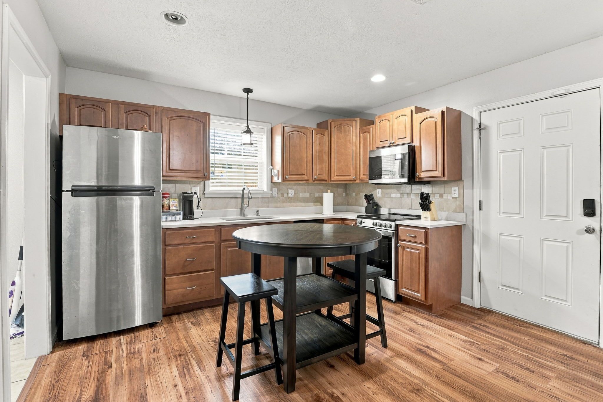 A kitchen with wooden cabinets, a stainless steel refrigerator, a microwave, and a stove.