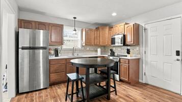 A kitchen with wooden cabinets, a stainless steel refrigerator, a microwave, and a stove.