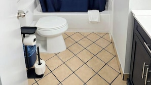 A bathroom with a white toilet, a bathtub, and a blue shower curtain. - New updated Daytona Oceanview w/kitchenette, pool (Daytona Beach)