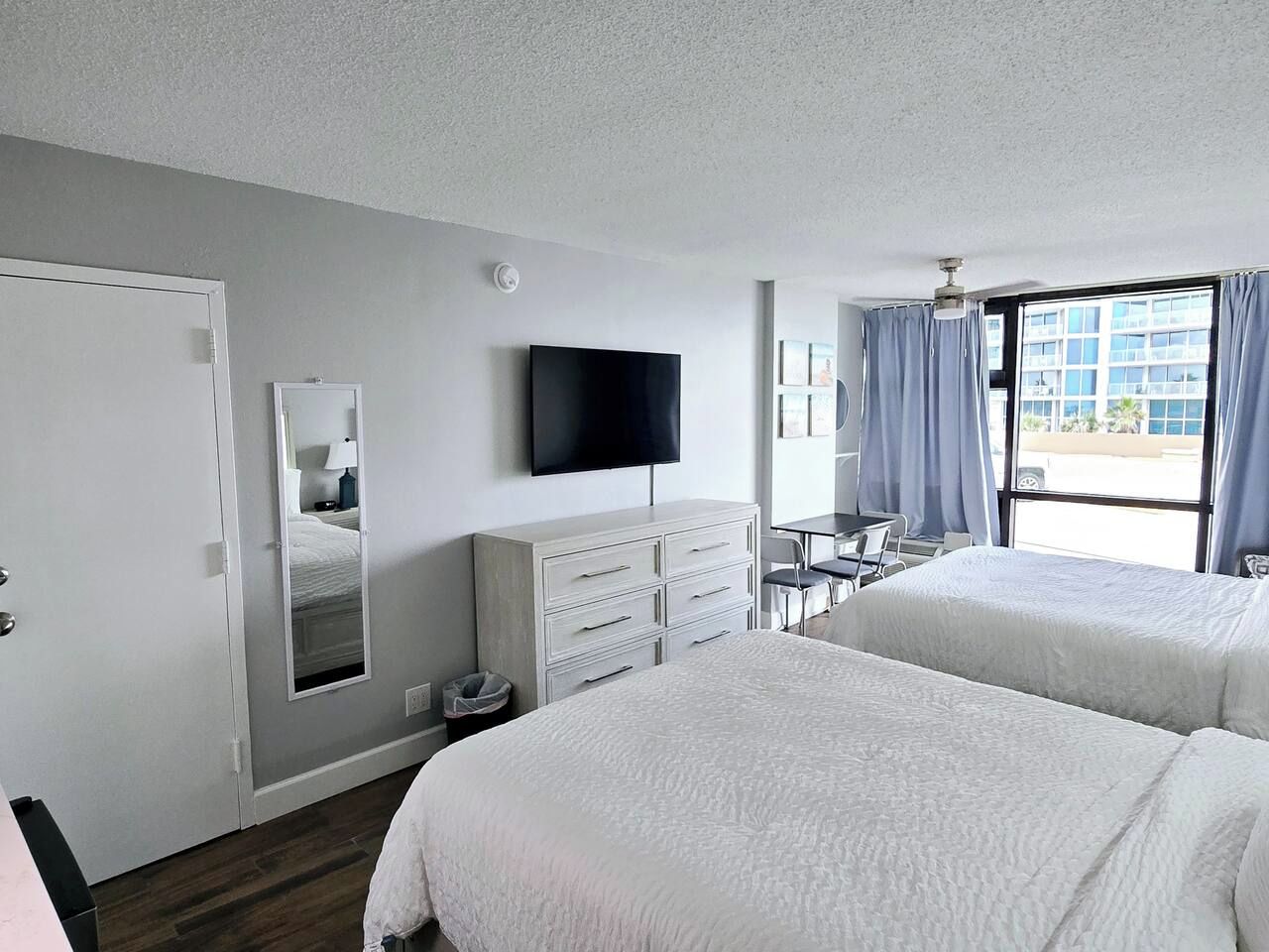 Habitación de hotel con dos camas, una televisión de pantalla plana, un escritorio y una ventana con cortinas.