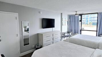 Habitación de hotel con dos camas, una televisión de pantalla plana, un escritorio y una ventana con cortinas.
