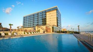 Un hotel moderno con una piscina grande y sillones de sol.