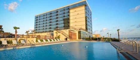 Un hotel moderno con una piscina grande y sillones de sol.