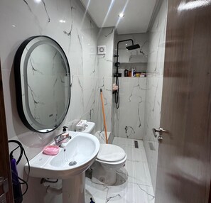 A bathroom with a sink, toilet, mirror, shower, and marble walls. - 5 min to Mohammed VI Hospital + 15 min to the airport (Bouskoura)