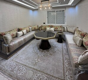 A modern living room with a glass coffee table, patterned sofas, and a decorative rug. - 5 min to Mohammed VI Hospital + 15 min to the airport (Bouskoura)