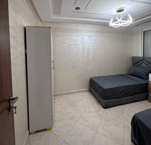 A bedroom with a bed, a wardrobe, and a ceiling light fixture. - 5 min to Mohammed VI Hospital + 15 min to the airport (Bouskoura)