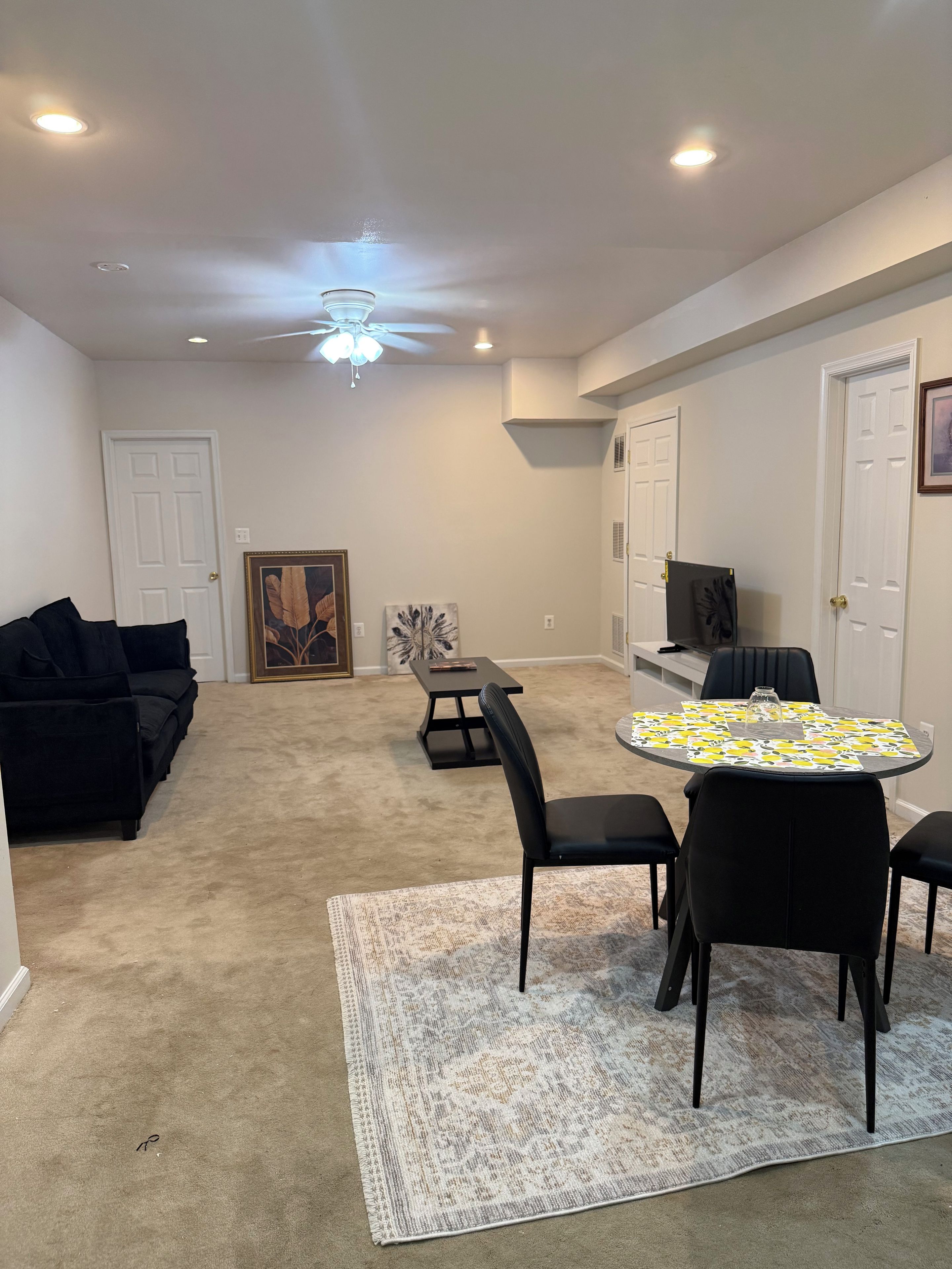 A room with a ceiling fan, recessed lighting, a dining table with chairs, a sofa, and a carpeted floor.