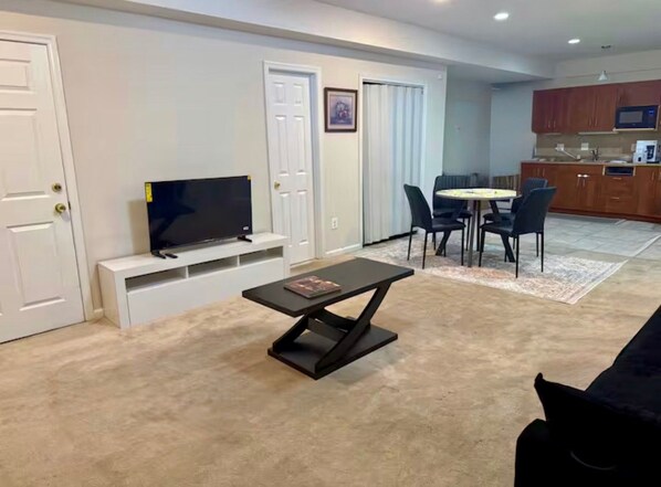 A living room with a TV, a coffee table, and a dining area with chairs.